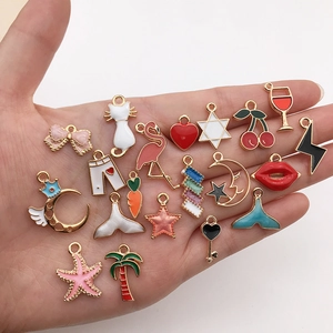 Assorted gold-plated enamel charms for DIY jewelry making displayed on a palm