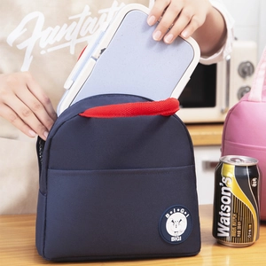 Navy canvas insulated lunch bag with red handles and round cartoon logo in a kitchen setting
