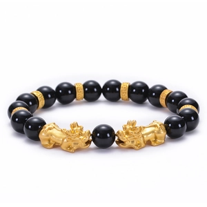 Macro detail of 10mm black onyx beads with golden Pixiu charms and engraved spacers