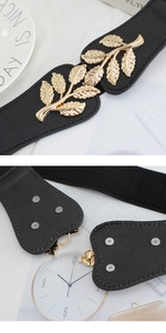 Detail of gold leaf buckle and silver rivets on a black elastic waist belt