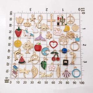 Assorted gold enamel charms with animals and plants on a measurement scale board