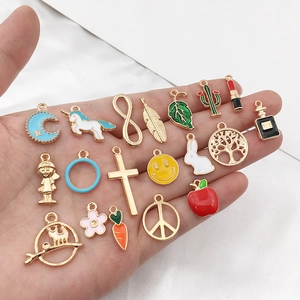 Close-up of mixed enamel alloy charms in hand featuring moons and colorful icons