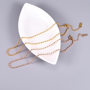 Close-up of minimalist gold and rose gold beaded necklaces with K18 engraving on a white tray