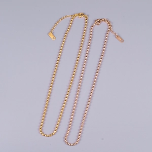 Macro view of gold and rose gold titanium bead chains with K18 engraved metal tags
