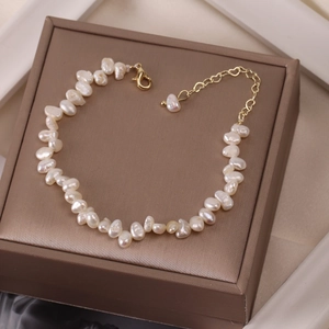 Close-up of natural baroque pearl bracelet with gold clasp on brown velvet jewelry box