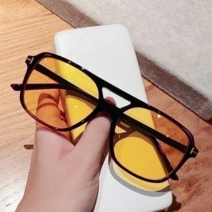 Detail of square pilot sunglasses with thick black frames and yellow tinted lenses