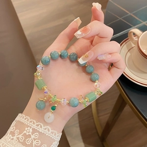 Close-up of elegant purple jade and green emerald safety buckle bracelet on woman's wrist