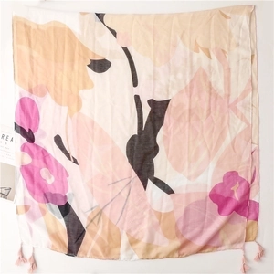Detail of floral print chiffon shawl with pink tassel accents on a white background