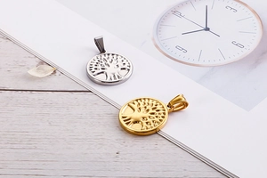 Detail of tree of life pendants in gold and silver finish on minimalist background