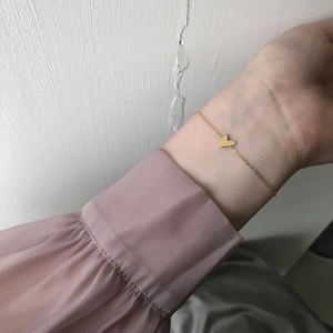 Minimalist gold heart pendant bracelet in titanium steel shown on woman's wrist