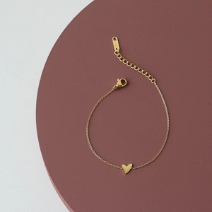 Detail of minimalist gold heart charm bracelet with adjustable chain and lobster clasp