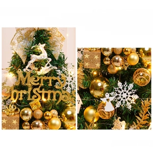Close-up of golden festive ornaments including baubles and elk on green pine branches