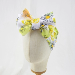 Close-up of white waffle fabric baby headband with yellow lemon print and large bow knot