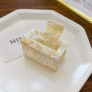 Elegant cream marble acetate square hair claw clip for women on a ceramic plate