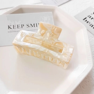 Detail of cream marble rectangular hair clip in a minimalist white ceramic tray