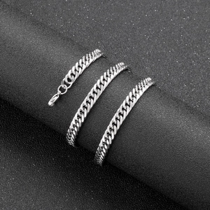 Close-up of polished silver stainless steel Cuban link chain on a black stand
