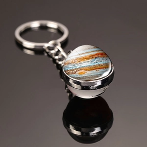 Macro shot of Jupiter pattern glass dome keychain with metal ring on reflective surface