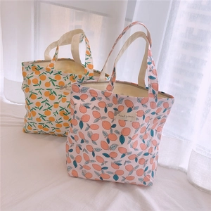 Détail de sacs fourre-tout en toile florale avec imprimés fruits et étiquettes textiles