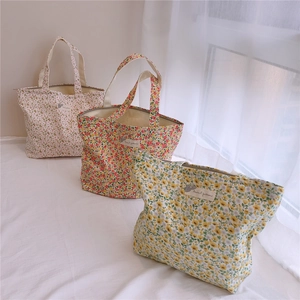 Détail de sacs en coton à fleurs avec étiquettes d'animaux sur un fond en tissu blanc