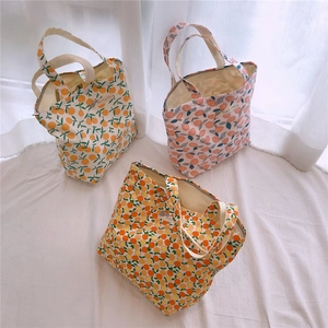 Trois sacs cabas en toile avec motifs de fruits et fermeture éclair sur tissu blanc