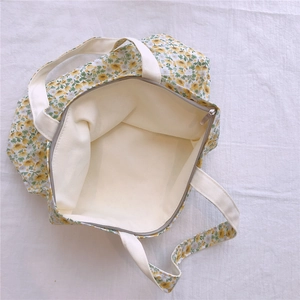 Détail d'un sac cabas en toile fleurie avec fermeture éclair et doublure en coton