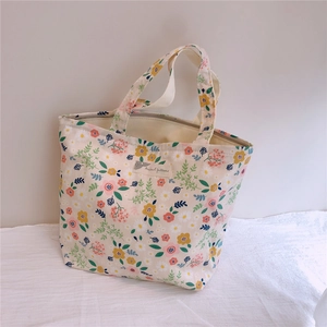 Détail d'un petit sac en coton à fleurs avec fermeture éclair en métal et étiquette