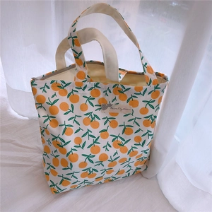 Gros plan du petit sac en coton blanc avec motif d'oranges et étiquette en tissu
