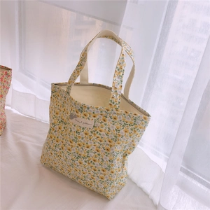 Détail du motif floral jaune sur un sac en toile avec une étiquette blanche tissée