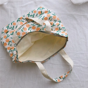 Vue de dessus d'un sac cabas en toile à motif floral orange avec fermeture zippée