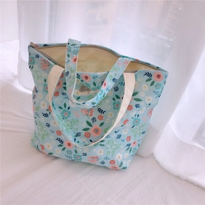 Gros plan du petit sac fourre-tout à fleurs bleues avec texture toile et fermeture éclair