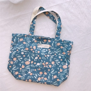 Détail du sac cabas bleu fleuri en coton avec étiquette motifs animaux et anses toile
