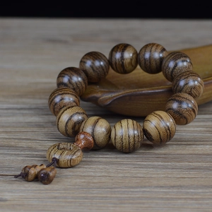 Polished Vietnamese white sand oud wood prayer beads with tiger stripe texture on wooden tray