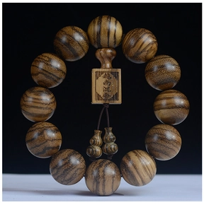 Macro detail of natural Agarwood prayer beads with engraved wooden plaque and rich texture