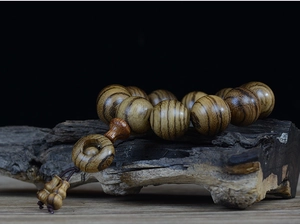 Detailed view of 108 agarwood beads with tiger stripe texture on a rustic branch