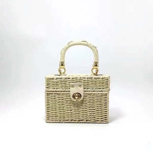 Detail of beige woven box bag featuring textured straw material and gold twist lock