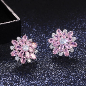 Macro shot of luxury pink flower stud earrings with zircon stones on a blue display