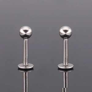 Classic G23 titanium labret studs with round ball and flat base on reflective surface