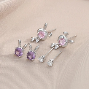 Detail of bunny stud earrings set with purple and pink zircon stones on satin