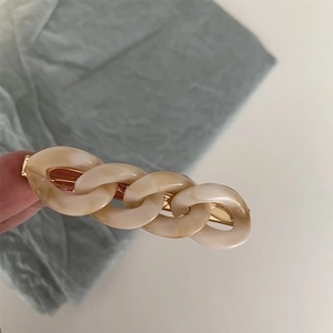 Detail shot of vintage cream marble chain hair clip with golden metal base