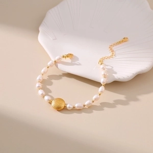 Detail view of handmade freshwater pearl bracelet with a golden textured metal bead focal point