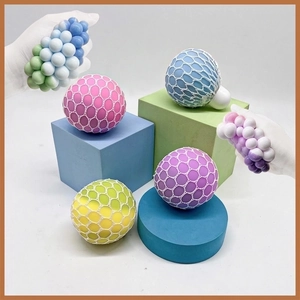 Colorful stress relief squishy mesh balls in pink, blue and purple on geometric stands