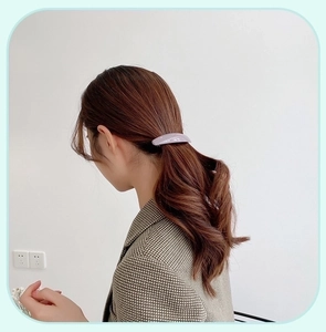 Detail of elegant lavender acrylic spring hair clip styled on a wavy brunette ponytail