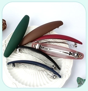 Set of six matte spring hair clips in various vintage colors displayed on a ceramic plate