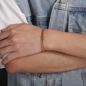 Close-up of golden Cuban link chain bracelet on a model wearing a denim jacket
