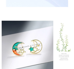 Detail of asymmetric celestial earrings with gradient moon and green star design