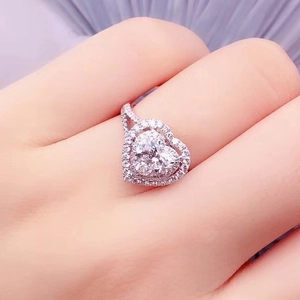 Close-up of heart-shaped Moissanite ring with diamond halo on silver band for women