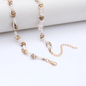 Macro view of shell and pearl beaded necklace with golden lobster clasp and extension chain