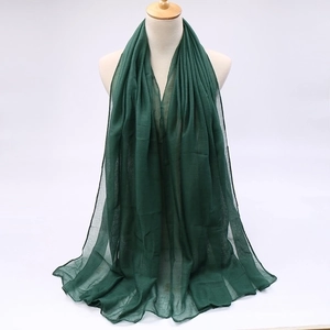 Detailed texture of lightweight dark green voile scarf on a beige mannequin bust
