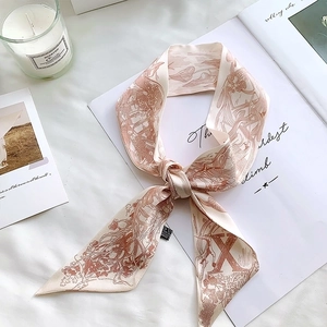 Detailed view of retro silk scarf with hand-drawn red illustrations on beige fabric