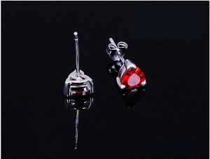 Macro view of heart-shaped red gemstone earrings with silver three-prong setting